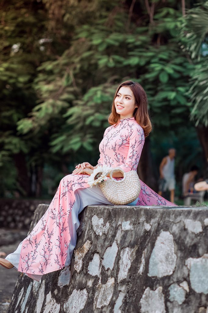 越南穿粉色奥黛的漂亮混血美女坐在堤坝上