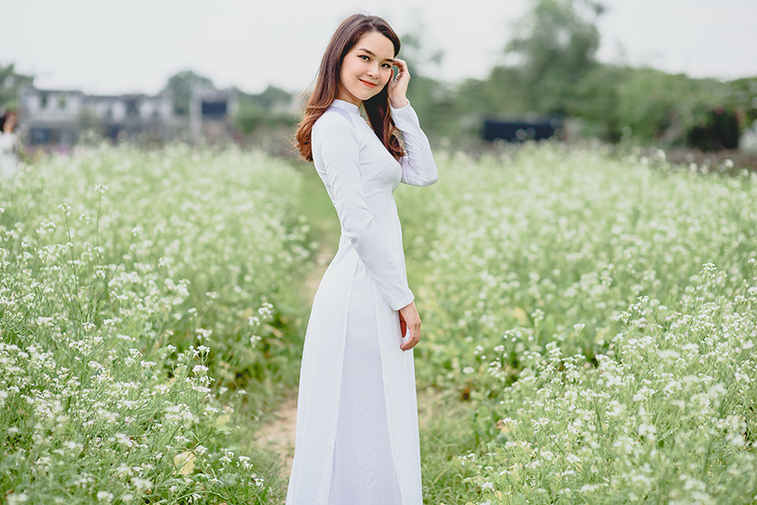 穿着白色奥黛在花丛中的越南女孩